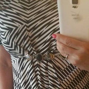 May include: A black and white striped dress with a silver and black belt. The dress has a pocket on the left side.