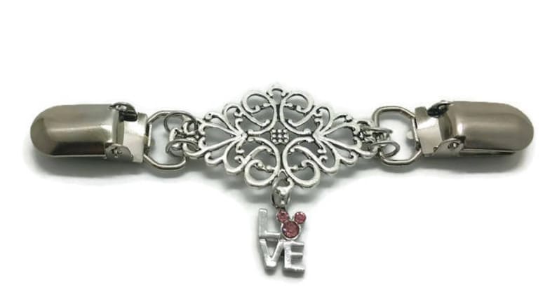 May include: Silver tone decorative clasp with a filigree design and a dangling charm that says "LOVE" with a pink Mickey Mouse head.