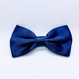 May include: A dark blue bow tie made of satin fabric.