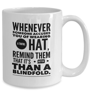 Peut inclure: Une tasse &agrave; caf&eacute; en c&eacute;ramique blanche avec du texte noir qui dit "Whenever someone accuses you of wearing a tinfoil hat, remind them that it's better than a blindfold."