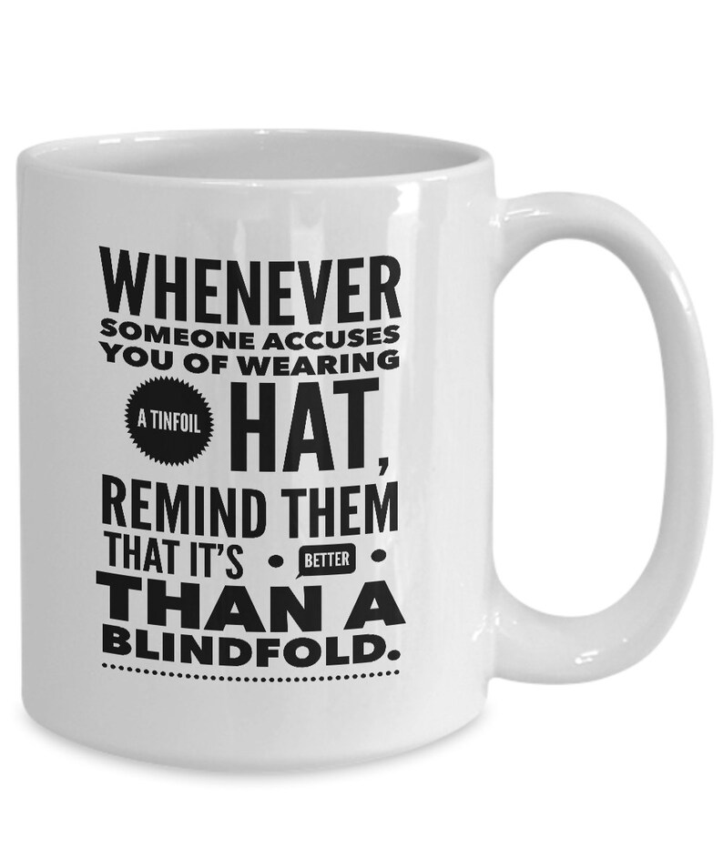 Peut inclure: Une tasse &agrave; caf&eacute; en c&eacute;ramique blanche avec du texte noir qui dit "Whenever someone accuses you of wearing a tinfoil hat, remind them that it's better than a blindfold."