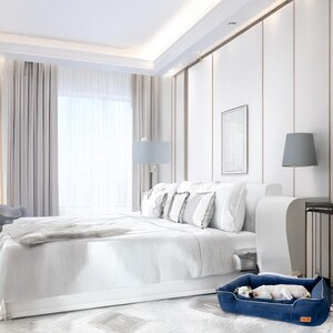 K&ouml;nnte beinhalten: Ein luxuri&ouml;ses Schlafzimmer mit einem gro&szlig;en wei&szlig;en Bett, weichen Kissen und einer grauen Decke. Ein marineblaues Hundebett steht auf dem Boden, in dem ein kleiner wei&szlig;er Hund schl&auml;ft. Der Raum hat wei&szlig;e W&auml;nde und ein gro&szlig;es Fenster.