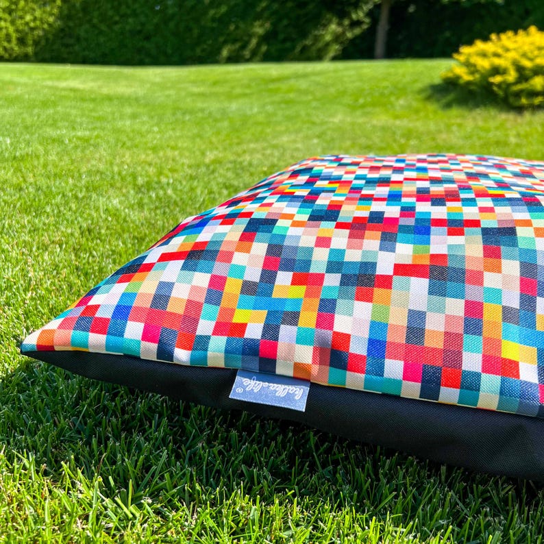 May include: A colorful dog bed with a geometric pattern of squares in various shades of red, blue, yellow, green, and white. The bed has a black border and a "Happy Life" logo.