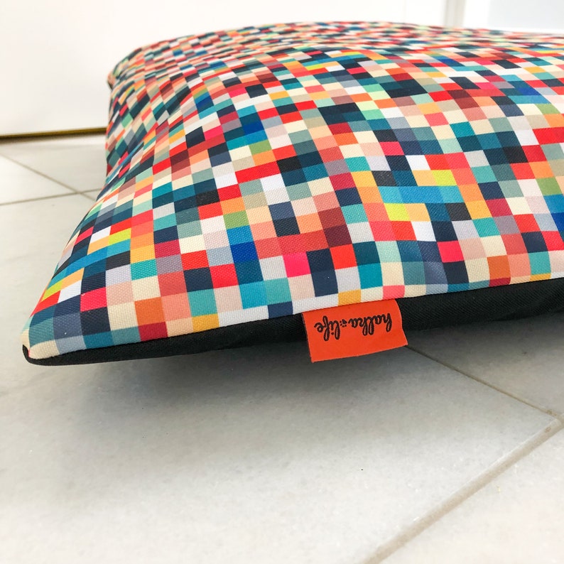 May include: A colorful rectangular dog bed with a black border and a red label that says "Ruffle + Life".