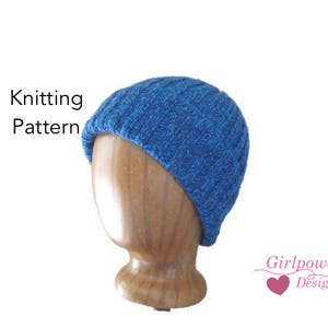 May include: A blue knitted hat displayed on a wooden head form. The hat has a textured pattern and is made of a vibrant blue yarn. The words "Knitting Pattern" are visible in the image, along with the text "Girlpower Designs".