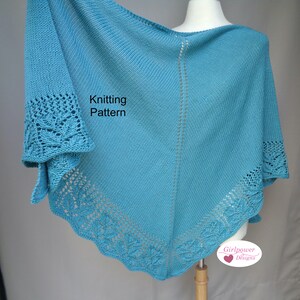 May include: A teal blue knitted shawl with a lace border. The shawl is draped over a mannequin. The text "Knitting Pattern" is visible on the shawl. The text "Girlpower Designs" is visible in the lower right corner of the image.