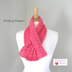 Op de afbeelding: Een roze gebreide sjaal met een kantpatroon. De sjaal wordt getoond op een wit mannequin. De tekst "Knitting Pattern" is zichtbaar bovenaan de afbeelding. De tekst "Girlpower Designs" is zichtbaar onderaan de afbeelding.