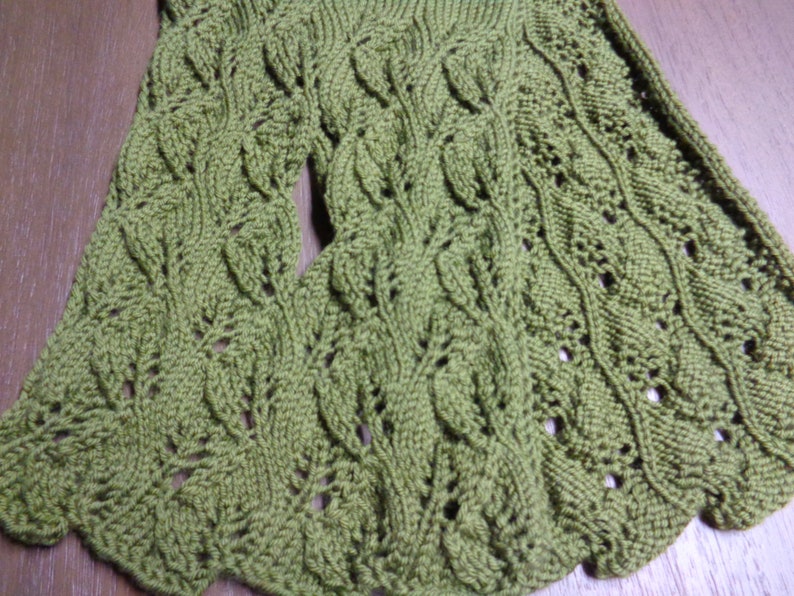 Pode incluir: Uma echarpe de malha verde com um padr&atilde;o de folhas. A echarpe &eacute; feita com um ponto delicado e tem um toque macio e texturizado.
