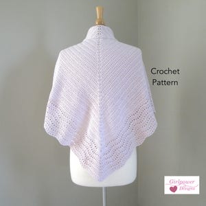 May include: A white crochet shawl on a dress form. The shawl has a delicate, lacy pattern and is crocheted in a single color. The text "Crochet Pattern" is visible in the image. The text "Girlpower Designs" is also visible in the image.