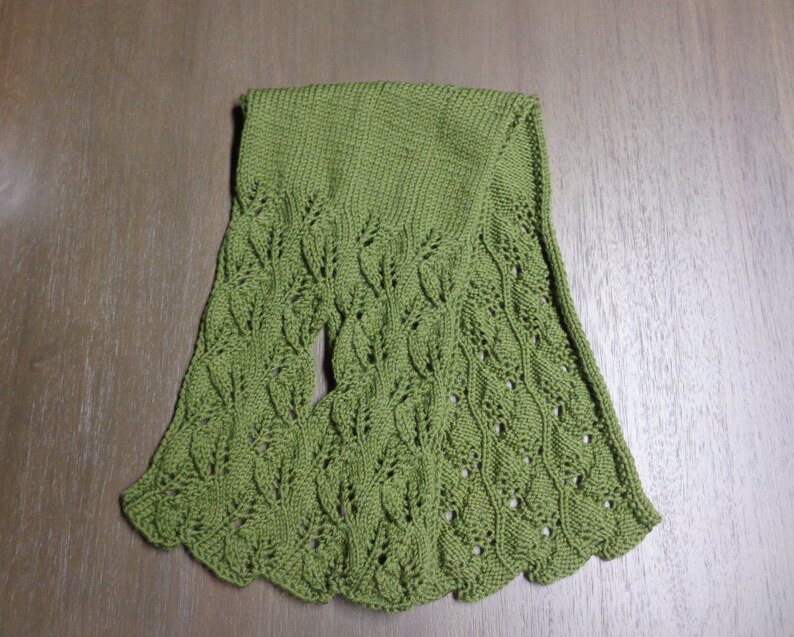 Pode incluir: Uma echarpe de malha verde com um padr&atilde;o de folhas.