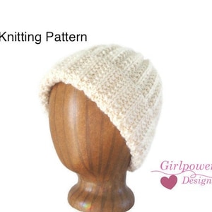 May include: Knitting pattern for a white beanie hat. The hat is shown on a wooden hat form. The text "Girlpower Designs" is visible in the bottom right corner of the image.
