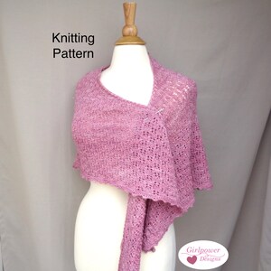 Op de afbeelding: Een roze gebreide sjaal, getoond op een mannequin. De sjaal is vastgezet met een speld en heeft een delicaat open patroon. De tekst "Knitting Pattern" is zichtbaar. De sjaal heeft een zachte, gedempte roze kleur. Girlpower Designs.