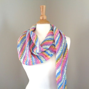 Pode incluir: Uma echarpe listrada colorida em tons de rosa, azul, verde e amarelo é drapeada em torno de um manequim de madeira.