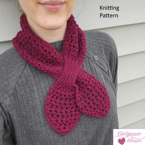 May include: A deep magenta knitted scarf featuring an openwork lace pattern and a central ribbed section that allows the ends to loop through. The text Knitting Pattern is visible at the top right, and a Girlpower Designs logo is at the bottom right.