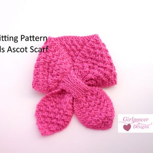 May include: A knitted pink ascot scarf for kids. The scarf is made of a textured knit fabric and features a unique design with two flared ends. The image includes the text "Knitting Pattern Kids Ascot Scarf".