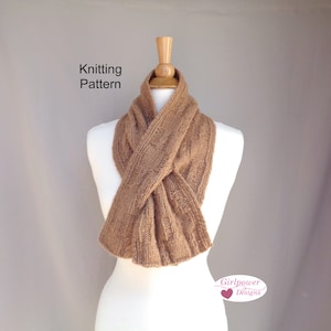 May include: A brown knitted scarf with a cable knit pattern, displayed on a mannequin. The scarf is folded in a way that shows the pattern and texture. The text "Knitting Pattern" is visible at the top of the image. The text "Girlpower Designs" is visible at the bottom of the image.