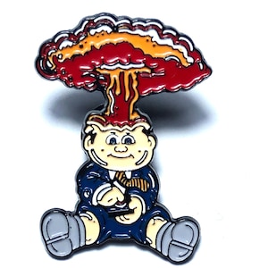May include: A cartoon pin of a person with a mushroom cloud exploding from their head. The person is wearing a blue suit and a tie. The pin is made of metal and has a shiny finish.