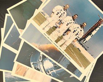 May include: A set of eight vintage photographs of the Apollo 9 mission. The photos feature the astronauts in their spacesuits, standing in front of the rocket. The text on the photos reads "Apollo 9 Crew: Russell L. Schweickart, David R. Scott, James A. McDivitt" and "Apollo 9 - Astronaut Scott Stands In..."