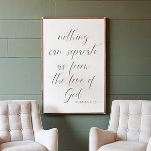 May include: A white framed sign with the text "nothing can separate us from the love of God" and the scripture reference "Romans 8:36". Two light gray upholstered armchairs with tufted backs and black legs sit in front of the sign.