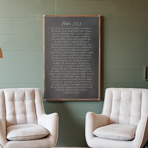 May include: Two light gray upholstered armchairs with button tufting and black legs with gold tips. A framed chalkboard with the text "Psalm 103" hangs on a green wall. A woven pendant lamp hangs in the upper left corner.