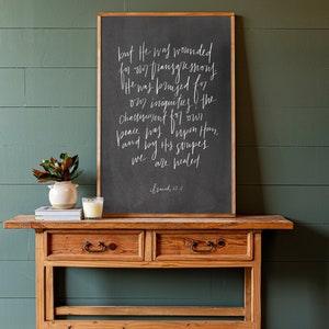 May include: A rustic wooden console table with two drawers and a black chalkboard sign with white calligraphy that reads "but He was wounded for our transgressions. He was bruised for our iniquities; the chastisement for our peace was upon Him, and by His stripes we are healed. Isaiah 53:5"