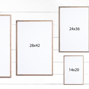 May include: Six different sized picture frames with white mats and wood frames. The frames are arranged in a row on a white wood background. The dimensions of each frame are written on the mat: 32x48, 28x42, 24x36, 20x30, 17x25, and 14x20.