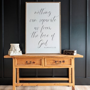 May include: A wooden console table with two drawers and a framed print with the text "nothing can separate us from the love of God ROMANS 8:38".