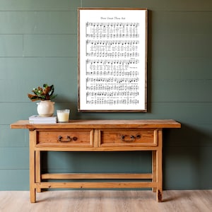 May include: A wooden console table with two drawers and a framed print of the hymn "How Great Thou Art" hanging on a green wall.