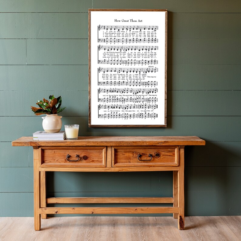 May include: A wooden console table with two drawers and a framed print of the hymn "How Great Thou Art" hanging on a green wall.