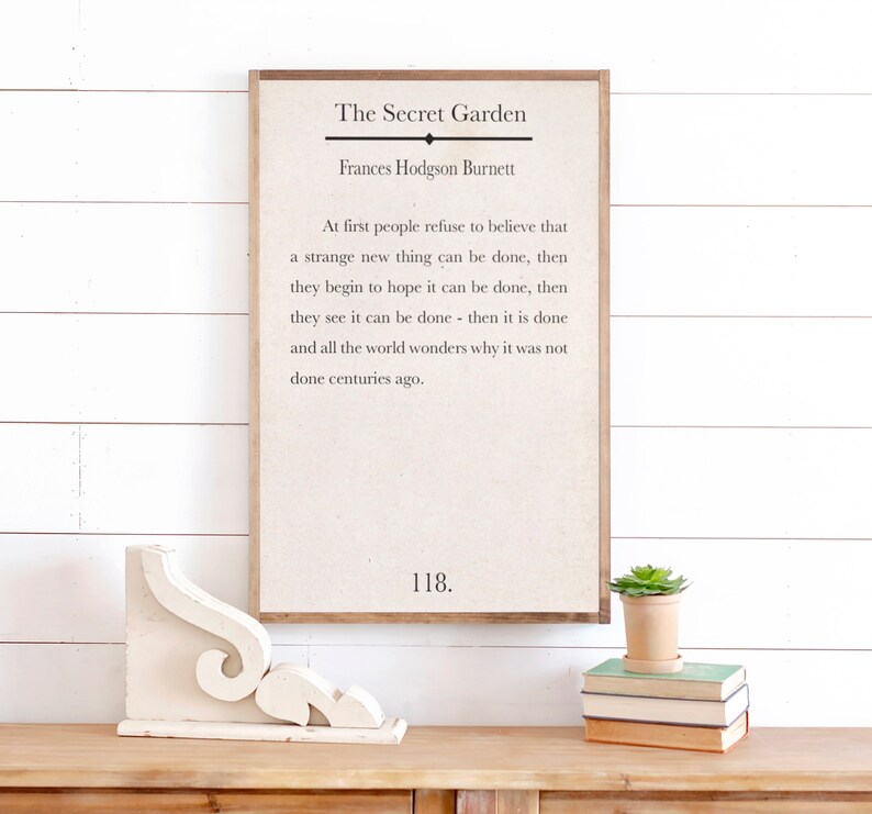 May include: A framed print with a white background and black text. The text reads "The Secret Garden" by Frances Hodgson Burnett. The quote reads "At first people refuse to believe that a strange new thing can be done, then they begin to hope it can be done, then they see it can be done - then it is done and all the world wonders why it was not done centuries ago." The number 118 is printed at the bottom of the print.