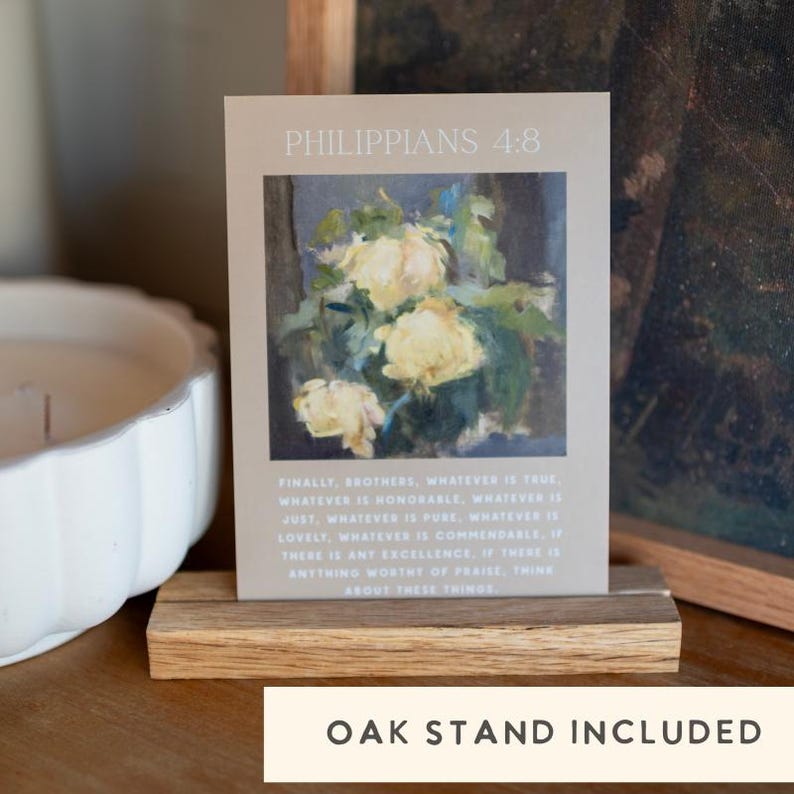 May include: A card with the text "PHILIPPIANS 4:8" and a floral painting, displayed on a wooden oak stand. The card features a quote about thinking about things that are true, honorable, just, pure, lovely, and commendable.
