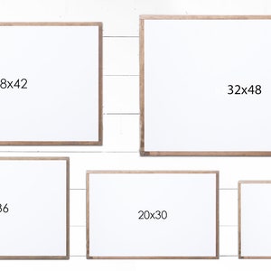 May include: Five different sized white picture frames with wood trim. The frames are arranged in a grid pattern on a white wood background. The frames are labeled with their dimensions in inches: 28x42, 32x48, 24x36, 20x30, and 17x25.