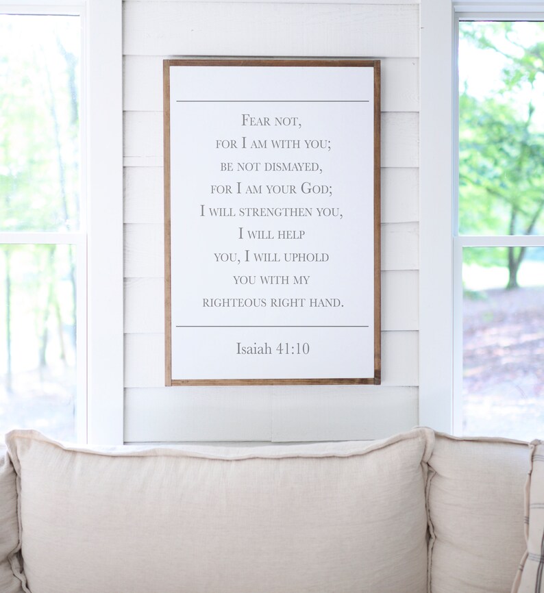 May include: A white wooden sign with a brown frame, featuring a bible verse from Isaiah 41:10. The verse reads "Fear not, for I am with you; be not dismayed, for I am your God; I will strengthen you, I will help you, I will uphold you with my righteous right hand."