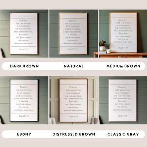 May include: Six different wood-framed prints of a Bible verse from Isaiah 41:10. The verse reads "Fear not, for I am with you; be not dismayed, for I am your God. I will strengthen you, I will help you, I will uphold you with my righteous right hand." The wood frames are in the following colours: dark brown, natural, medium brown, ebony, distressed brown, and classic grey.