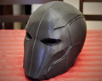 May include: A black 3D printed helmet with a detailed design and a visor. The helmet has a textured surface and a sleek, futuristic look.