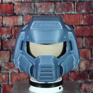 May include: A blue and gray 3D printed helmet with a visor. The helmet has a textured surface and a design that resembles a futuristic helmet.