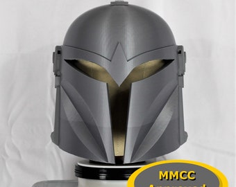 May include: A gray 3D printed helmet with a visor and a MMCC Approved label. The helmet is on a black and white stand.