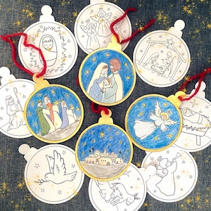 Puede incluir: Un conjunto de adornos navideños con temas religiosos. Los adornos presentan ilustraciones de la Natividad, ángeles y los Reyes Magos. Cada adorno tiene una parte superior dorada y una cuerda roja para colgar.