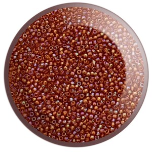 May include: A close-up image of a large quantity of small, round, copper-coloured beads. The beads have a metallic sheen and are arranged in a random pattern.