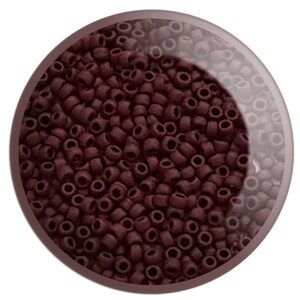 May include: A close-up image of a large quantity of small, dark brown seed beads. The beads are round and have a hole in the centre.