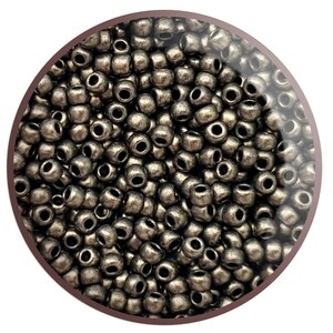 May include: A close-up view of a large quantity of small, round, dark grey beads. The beads have a metallic finish and are arranged in a random pattern.