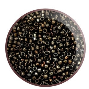 May include: A close-up image of a large quantity of small, round, metallic beads. The beads are a mix of black, brown, and copper colors.