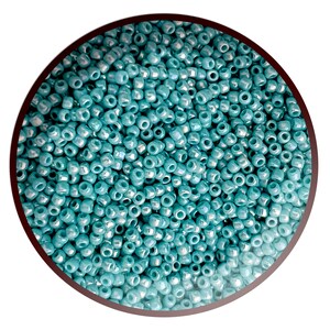 May include: A close-up view of a large quantity of teal blue seed beads. The beads are small and round, with a slight iridescent sheen.
