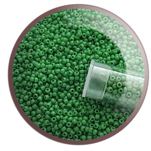 May include: A close-up of a clear plastic tube filled with small, round, green beads. The beads are scattered around the tube, creating a textured surface.