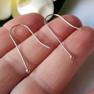 May include: A pair of silver hoop earrings with a small ball at the end of each hoop.