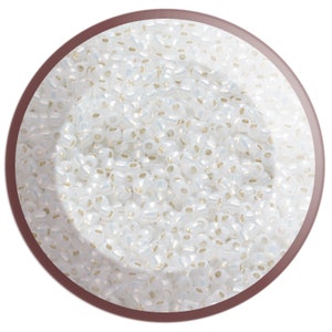 May include: A close-up view of a container filled with white seed beads. The beads are small and round, with a slight iridescent sheen.