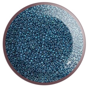 May include: A close-up image of a large quantity of small, dark blue seed beads. The beads are arranged in a random pattern and appear to be made of glass.