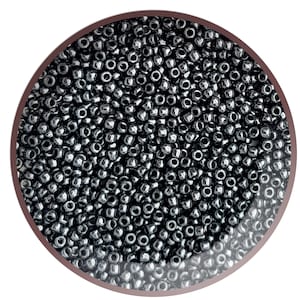 May include: A close-up view of a large quantity of small, round, black seed beads. The beads have a shiny, metallic finish.