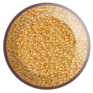 May include: A close-up image of a large quantity of small, round, golden-coloured beads. The beads are arranged in a circular pattern and appear to be made of glass or plastic.