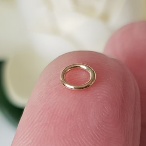 以下が含まれることがあります： 小さな金色のフープイヤリング。フープは滑らかで、シンプルで円形のデザインです。